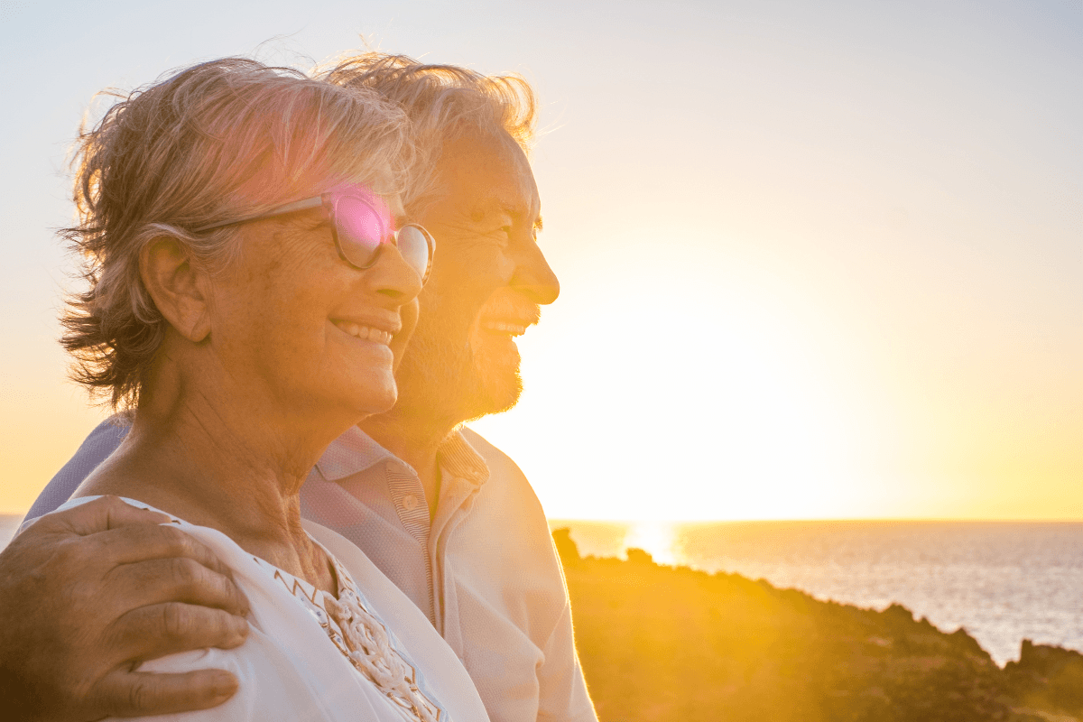 Couple of two happy seniors having fun in holiday trip together at vacations in the beach with the sea or ocean in the background.