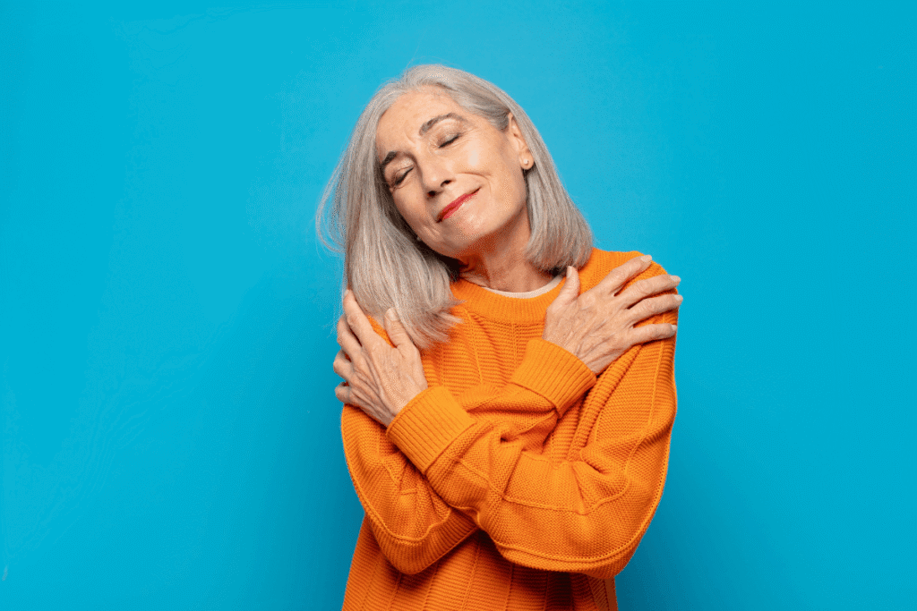 Mature aged woman feeling in love, smiling, cuddling and hugging self.